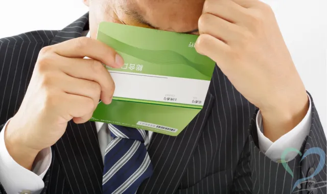 通帳片手に悩む男性