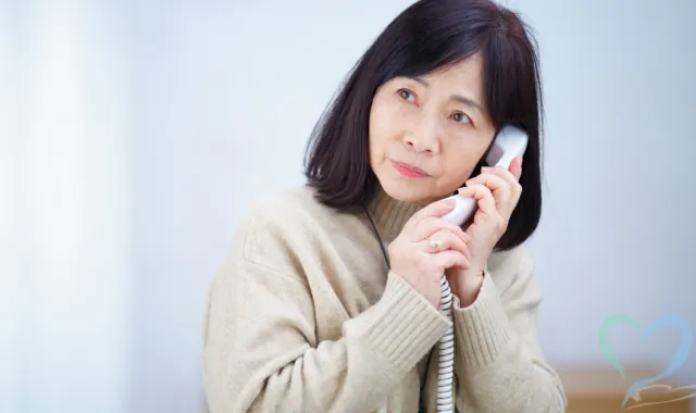 電話で話している中年女性