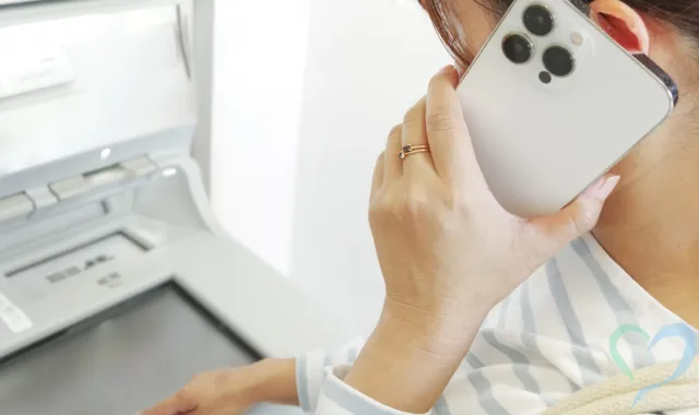 電話で話しながらATMを操作している